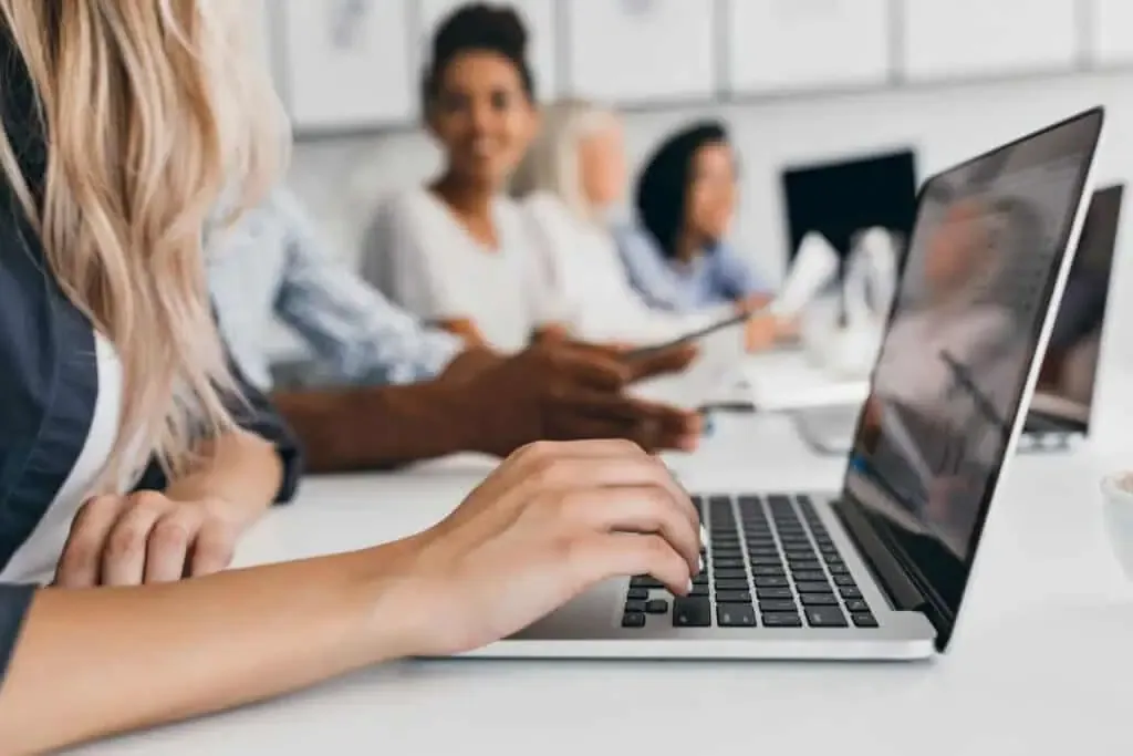 femme blonde avec une coiffure elegante en tapant du texte sur le clavier au bureau portrait interieur d employes internationaux avec secretaire a l aide d un ordinateur portable (1)