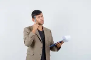 young male thinking something in grayish brown jacket,black shirt and looking concentrated. front view.